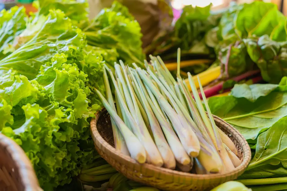 Several pale green lemongrass stalks with trimmed ends lying on a kitchen board.