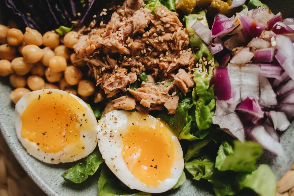 A bowl of mixed green leaves with halved boiled eggs, cucumber slices and cherry tomatoes.