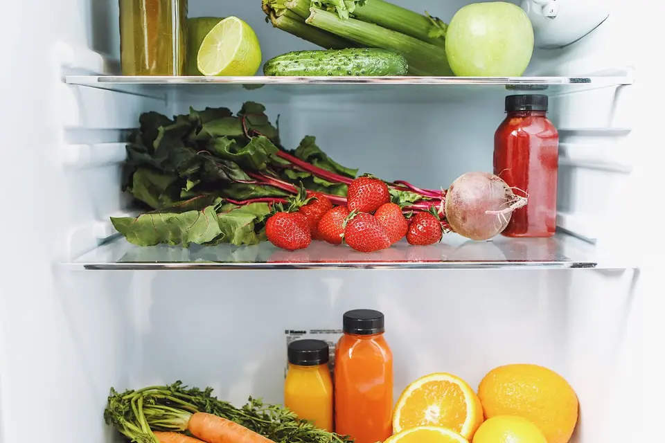 A tidy refrigerator shelf with vegetables and covered containers of leftovers.