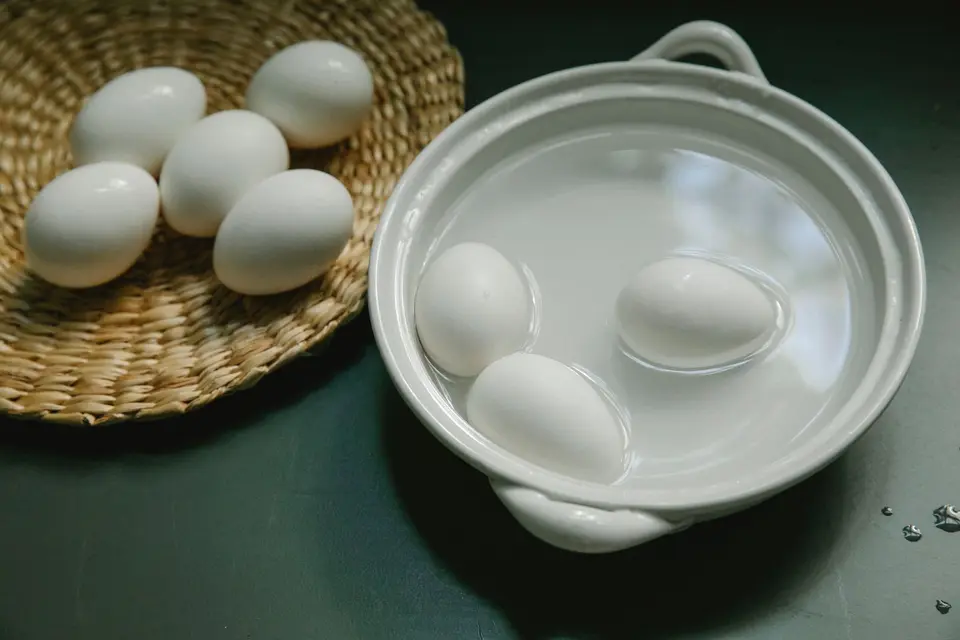 Halved boiled eggs with firm yellow yolks on a plain white plate beside a few unpeeled eggs.