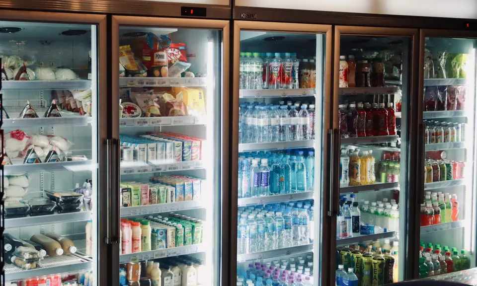 An open refrigerator with food sorted onto shelves, raw items in covered containers at the bottom.